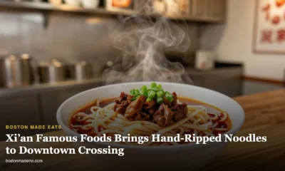 A steaming bowl of hand-pulled noodles with chili oil and cumin lamb in a modern noodle shop
