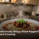 A steaming bowl of hand-pulled noodles with chili oil and cumin lamb in a modern noodle shop